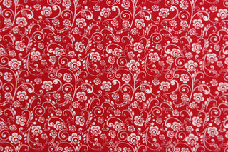 This fabric features a whimsical vine and floral design in white set against a red background.