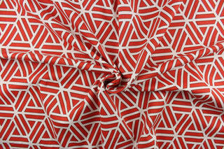 This fabric features a geometric abstract design in white, and red with black outline. 