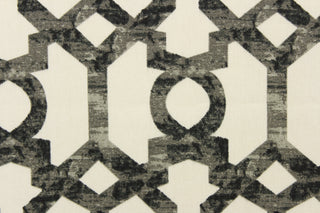  This fabric features a  geometric design in black and gray tones on an off white background. 