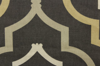 This fabric features a large geometric design in tan, light khaki, and taupe against a dark gray background. 