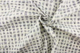  This printed fabric features abstract shapes in tones of gray on a cream background.