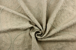 This fabric features an embossed medallion design in light green on a dark beige background.  