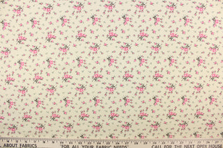 This quilting fabric features a  floral design in pink and green on a cream background. 