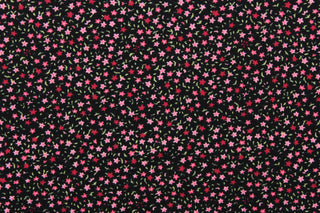 This jersey fabric features a dainty floral design in pink, green, and dark pink against black background.