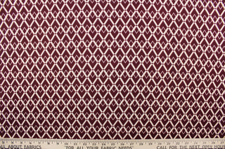 This 2way stretch lycra fabric features a geometric  design of diamonds in burgundy  and off white.