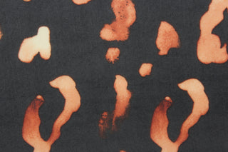 This chiffon fabric features a leopard design in a faded out orange against black. 