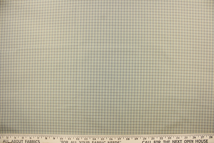 This yarn dye stripe fabric features a small plaid or checkered design in pale gray blue and beige.