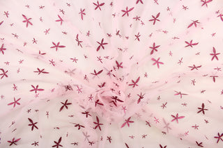 This tulle features a glittery star design dark pink against a pink background in . 