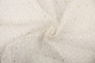 This lace features a woven floral design in white with a gold outline. 