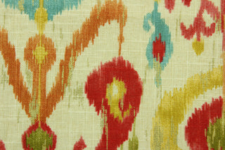  This printed fabric features an ikat geometric design in  orange, turquoise, rich pink, golden yellow, and olive green,   on a natural background with metallic gold accents.