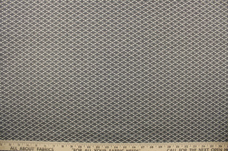 This fabric features a oval design in a cream, and shades of gray  with a latex backing.