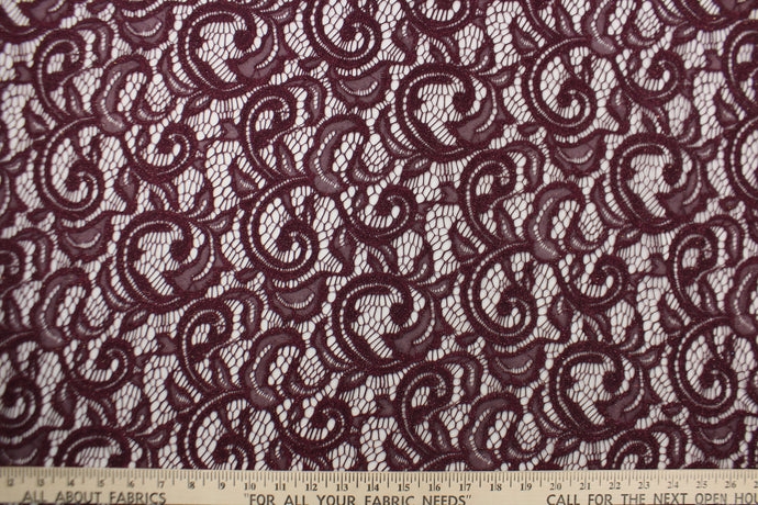 This lace features a floral design with glitter in a plum purple with a stretch. 