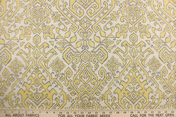 This fabric features an Aztec design in  yellow with gray outline against a natural background. 