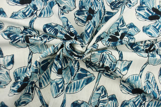 This fabric features a floral design in  varying shades of blue, black and hints of gray against a dull white background.