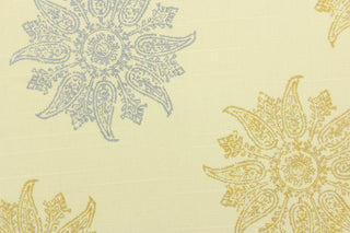 This fabric features a sun or flower design in gold and silver set against a creamy white. 