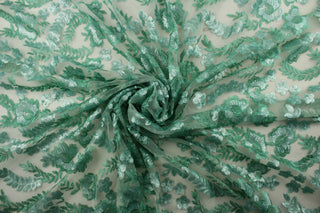 This green sequined fabric features an embroidered and sequined floral vine and delicate butterflies