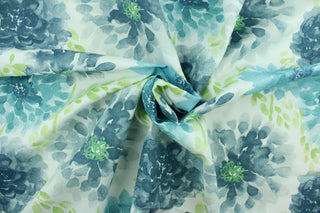 This screen printed fabric features large flowers in blue tones, turquoise and green set against a solid white background.