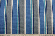 Load image into Gallery viewer,  Richloom Solarium© Savaro is a heavy-duty multipurpose outdoor fabric featuring a bold stripe pattern of gray, blue, turquoise, and beige.  It is extremely durable with a 10,000 double rub rating and has been tested to resist 500 hours of exposure to sunlight.  The fabric is also water and stain resistant.  Perfect for porches, patios and pool side.  Uses include toss pillows, cushions, upholstery, tote bags and more. 
