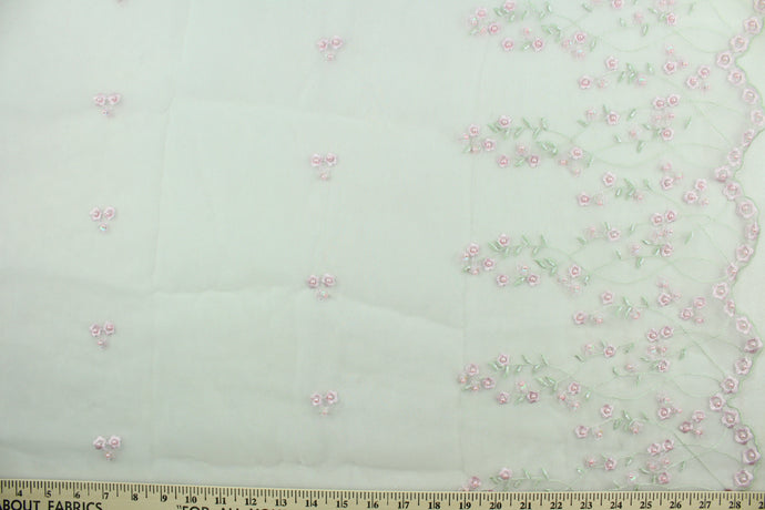 This fabric features a beautiful embroidered floral vine design with pink pearlized beads with a scalloped edge.  The sheer fabric is see through with a nice flowy drape.  It is perfect for special occasion apparel, costumes, overlays, table tops, décor, sheer curtains and more.  Colors include white, pink and green.