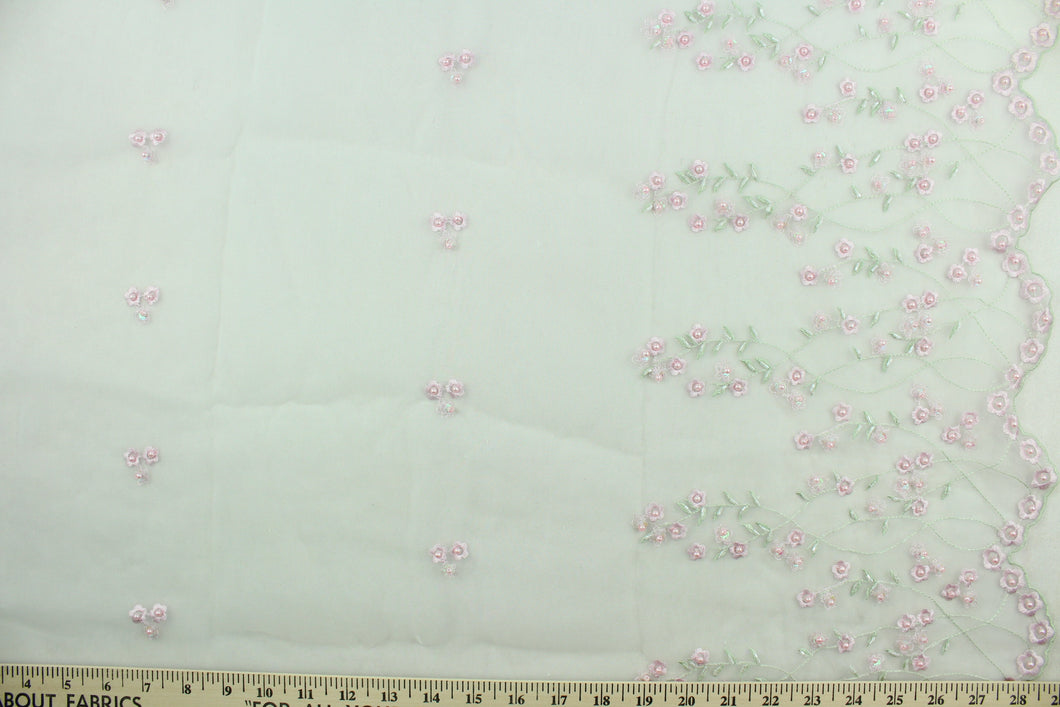 This fabric features a beautiful embroidered floral vine design with pink pearlized beads with a scalloped edge.  The sheer fabric is see through with a nice flowy drape.  It is perfect for special occasion apparel, costumes, overlays, table tops, décor, sheer curtains and more.  Colors include white, pink and green.