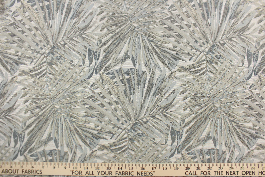 This jacquard fabric features a palm leaf design in gray, pale beige, pale blue and white . 