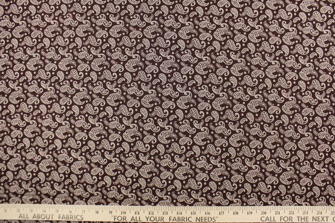  This fabric features a paisley design in white set against a brown background. 