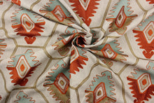 Load image into Gallery viewer, This tapestry features a vibrant embroidered Aztec design in orange. seafoam, and golden set against a light taupe.
