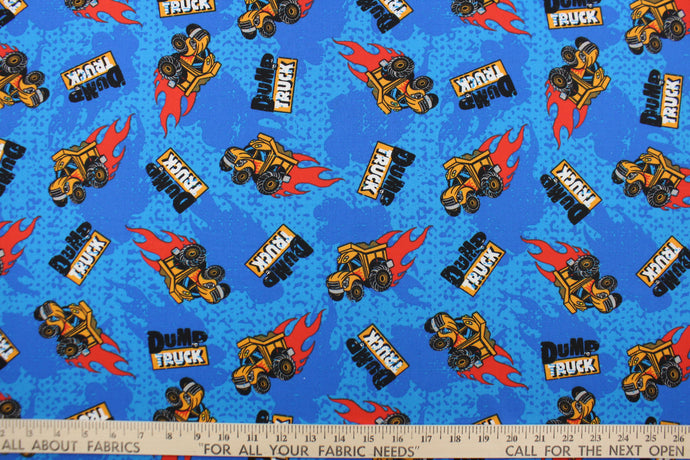 This fabric features a playful dump design in red, yellow, black, white, and gray set against a blue background.