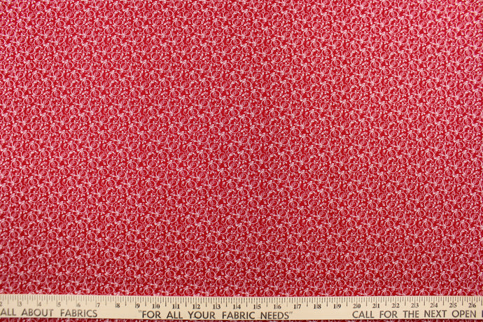 This fabric features a tiny floral vine design in white set against a red background. 