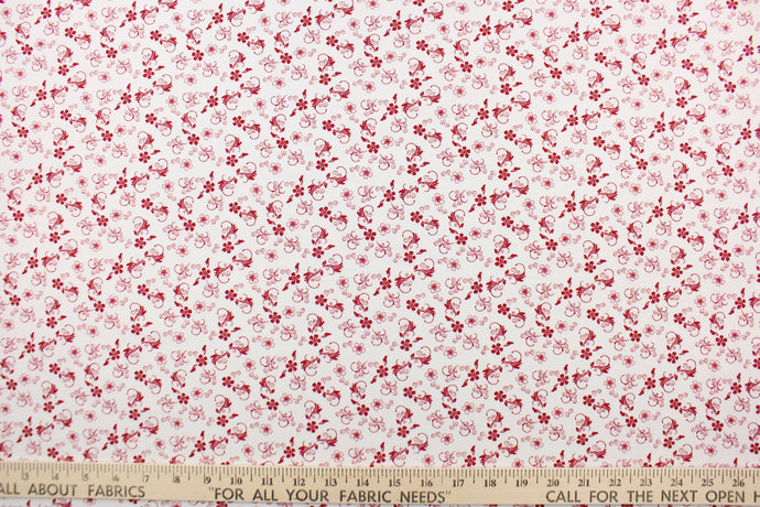 This fabric features a vine and floral design in red set against a white background.