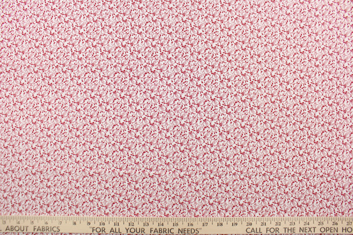 This fabric features a tiny vine design in red set against a white background .