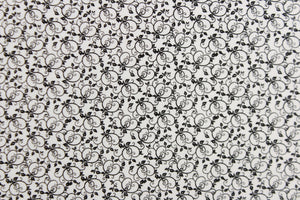 This fabric features a tiny vine design in black set against a white background .  