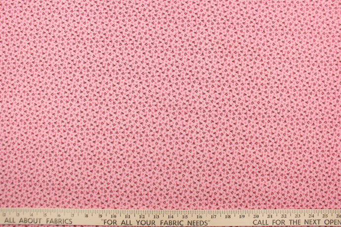  This fabric features a tiny floral design in pink, black and white set against a pink background.