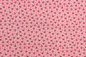  This fabric features a tiny floral design in pink, black and white set against a pink background.