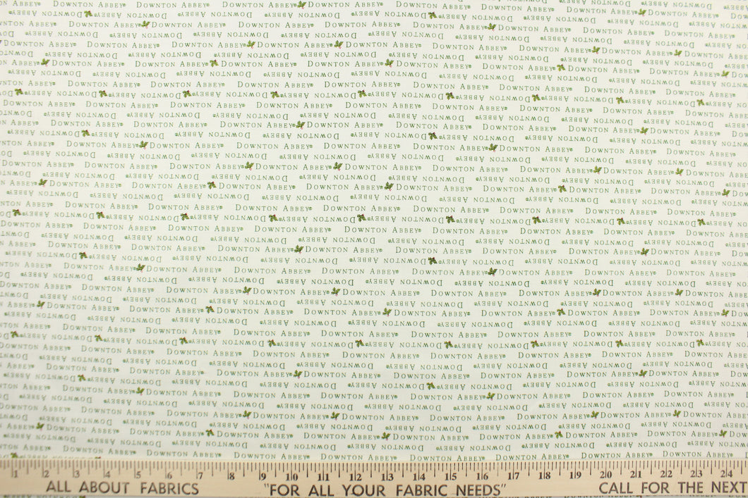 This quilting fabric feature  a Downtown Abbey print with a bit of holly in green against a white background .