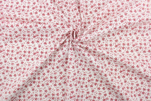 This fabric features a  floral design in red set against a white background.