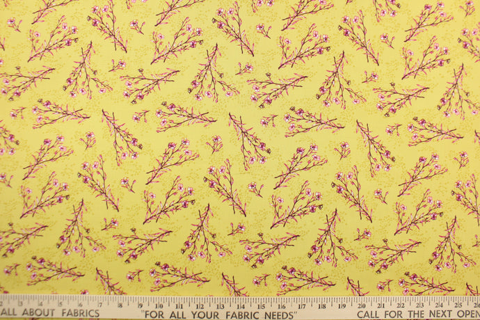 A floral branch design  in pink, white, and dark pink set against a mustard yellow.  