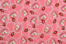 Load image into Gallery viewer, This quilting fabric features a cowboy/cowgirl theme with a rocking horse, rope and hat design in green, dark red, and white set against a medium pink background. 

