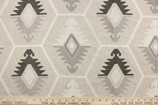 This tapestry features embroidered Aztec design in sliver, white, gray, and dark brown black set against a natural background . 