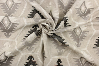 This tapestry features embroidered Aztec design in sliver, white, gray, and dark brown black set against a natural background . 