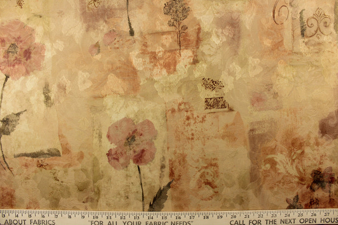 This jacquard offers a varying pattern of a flower mixed with lettering and a medallion in gold tones with muted gray, rose and brown colors. 