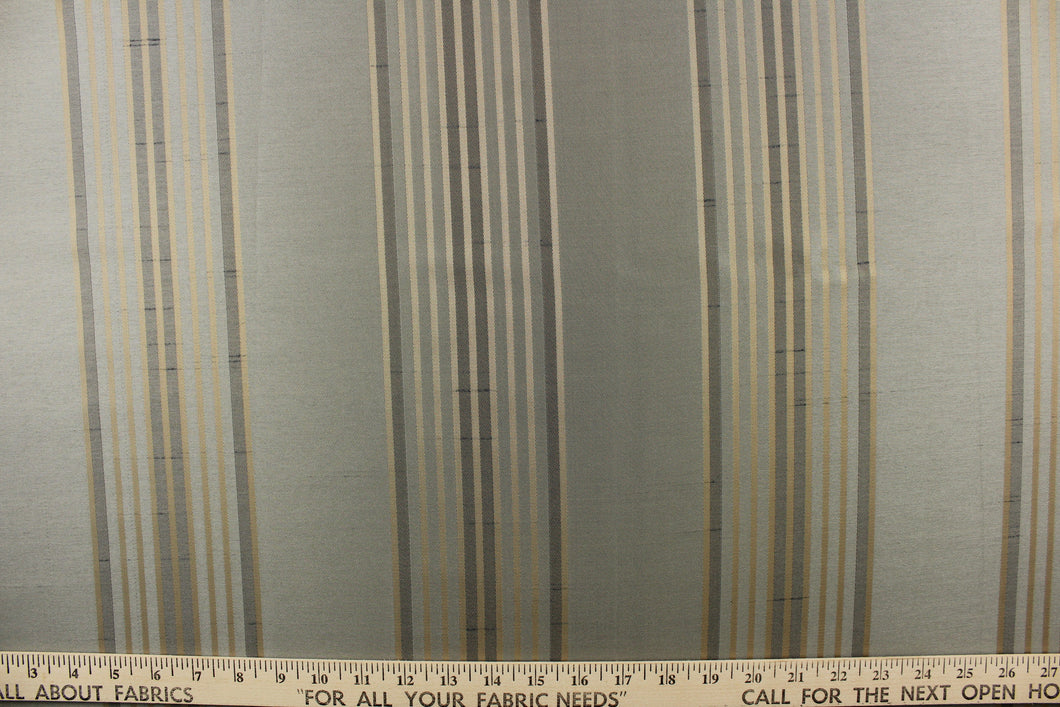 This fabric features a striped design in gold on a pale gray blue background