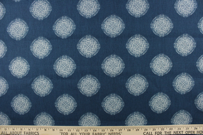  This fabric features a geometric design of circles in white on a blue background. 