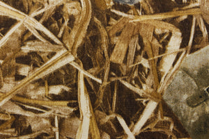  This fabric features a straw camouflage design in brown tones with items within the straw. 
