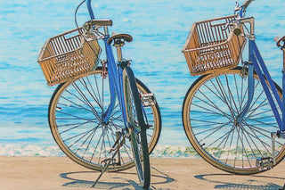 This fabric features a beautiful realistic view of two bikes along  the seashore in beige, blue, black and gray. 