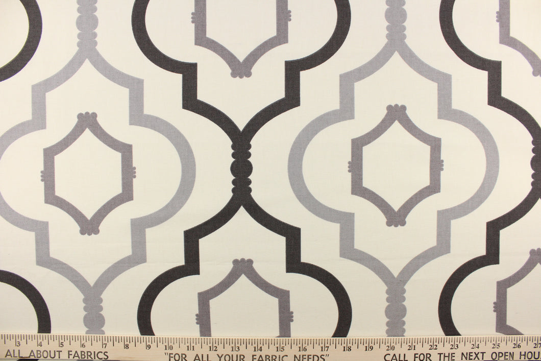 This fabric features a large geometric design in dark gray and gray on a off white background. 