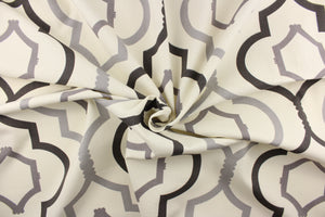 This fabric features a large geometric design in dark gray and gray on a off white background. 