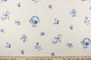 A floral blue blossom and butterfly pattern set against a creamy particulate background