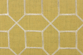 This embroidered fabric features a geometric design in white against a mustard yellow.
