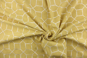 This embroidered fabric features a geometric design in white against a mustard yellow.